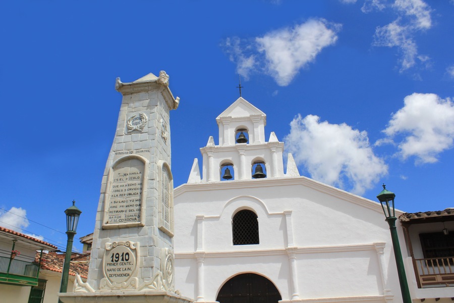 Una iglesia blanca con un campanario y una torre del reloj con inscripciones.