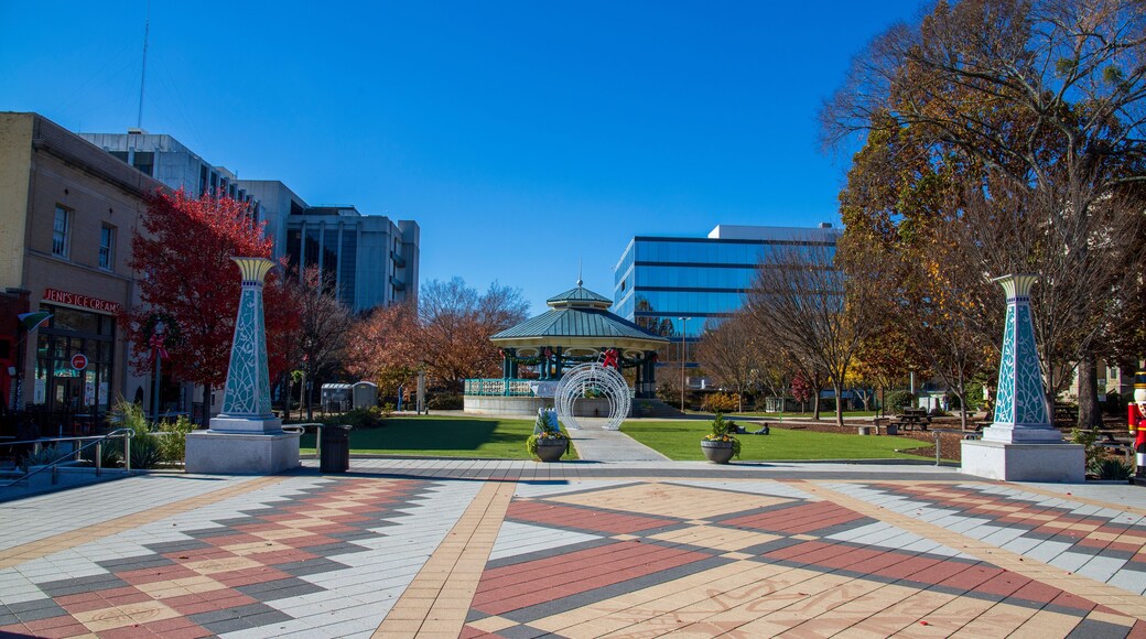 a gorgeous autumn landscape at the Decatur Square with red and yellow autumn trees, lush green trees and a round blue pergola, glass office buildings and clear blue sky in Decatur Georgia USA