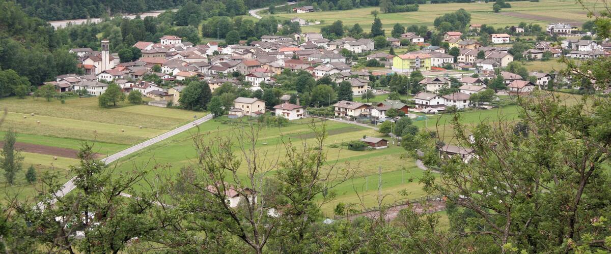 A village nestled in a valley with houses, a church, and surrounding greenery.
