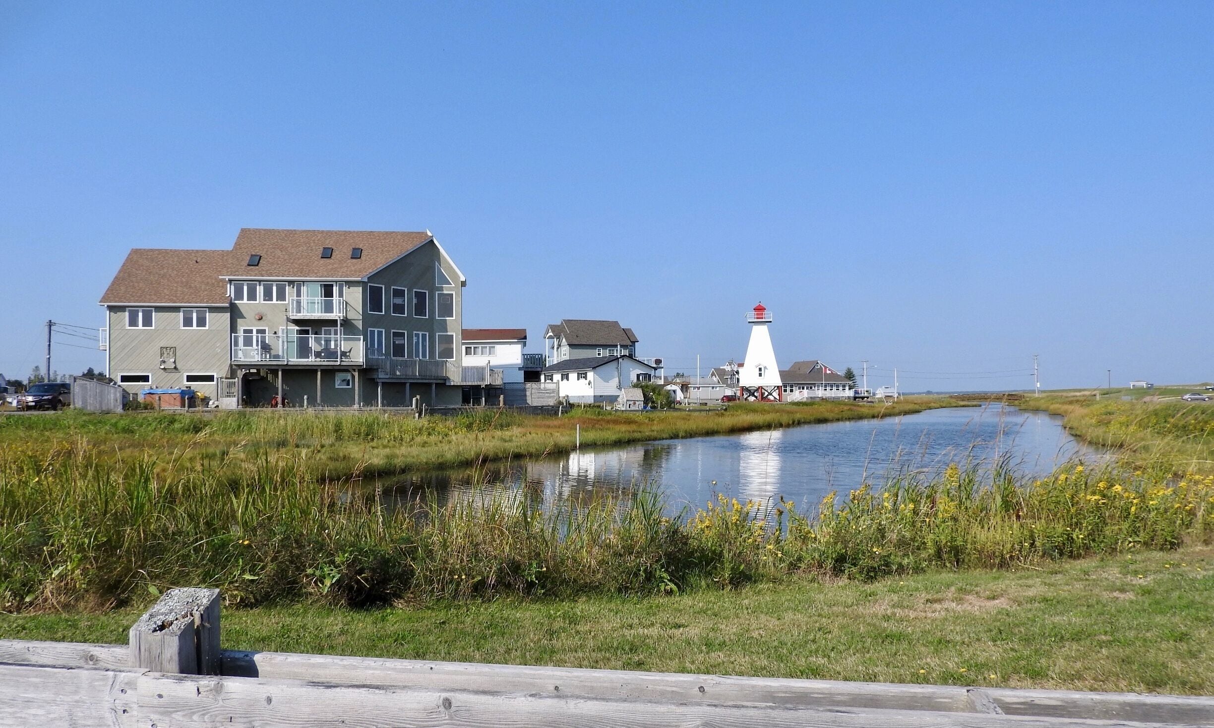 A canal with houses and a lighthouse by the water.