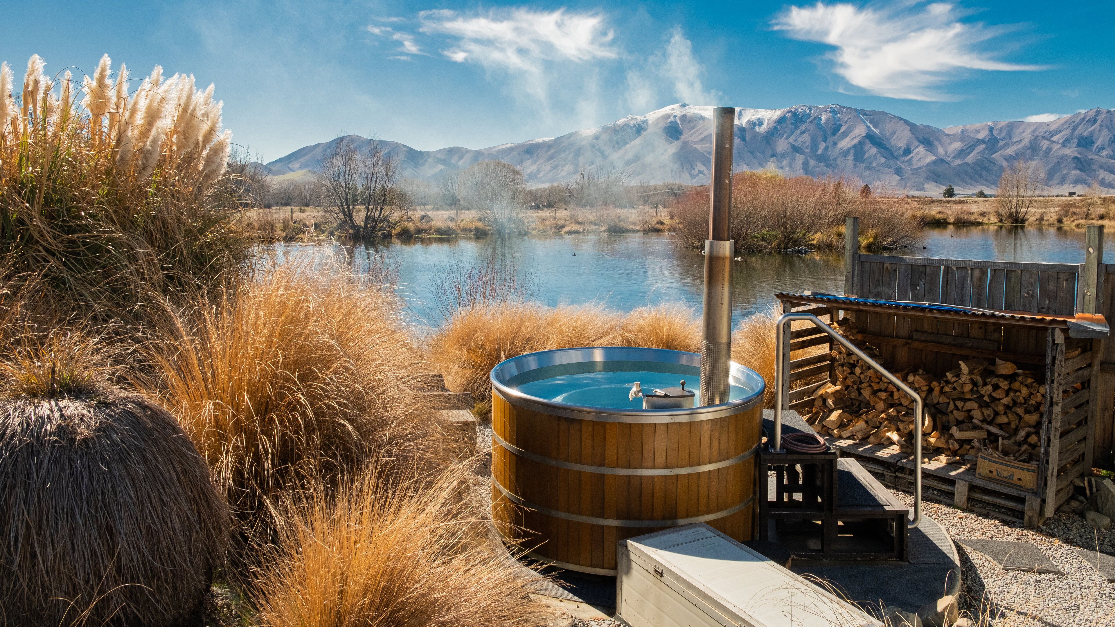 A hot tub by a lake with mountains in the background.