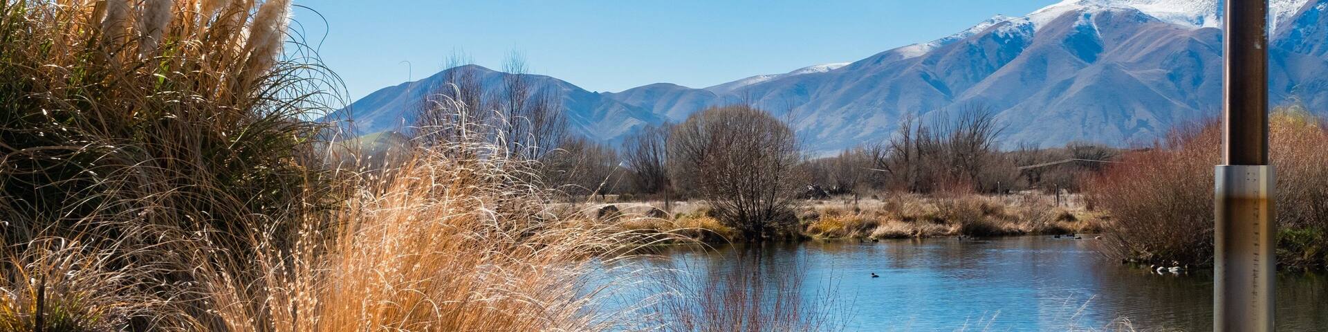 A hot tub by a lake with mountains in the background.