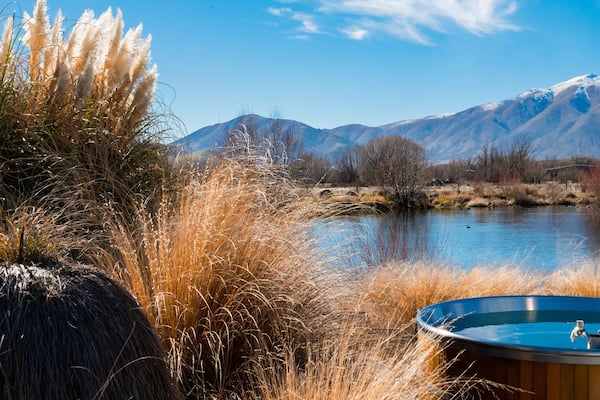 Un bain à remous au bord d’un lac, avec des montagnes en arrière-plan.
