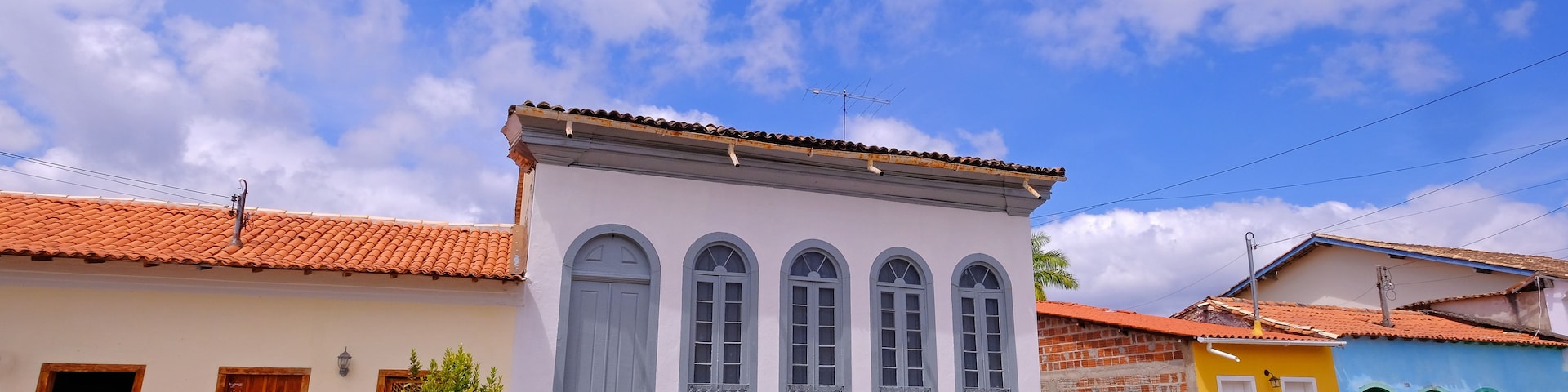 Una calle con edificios coloridos, un camino empedrado y un cielo azul despejado con nubes.
