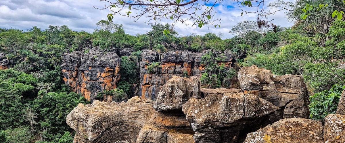 A rocky landscape with layered rock formations and dense green foliage.