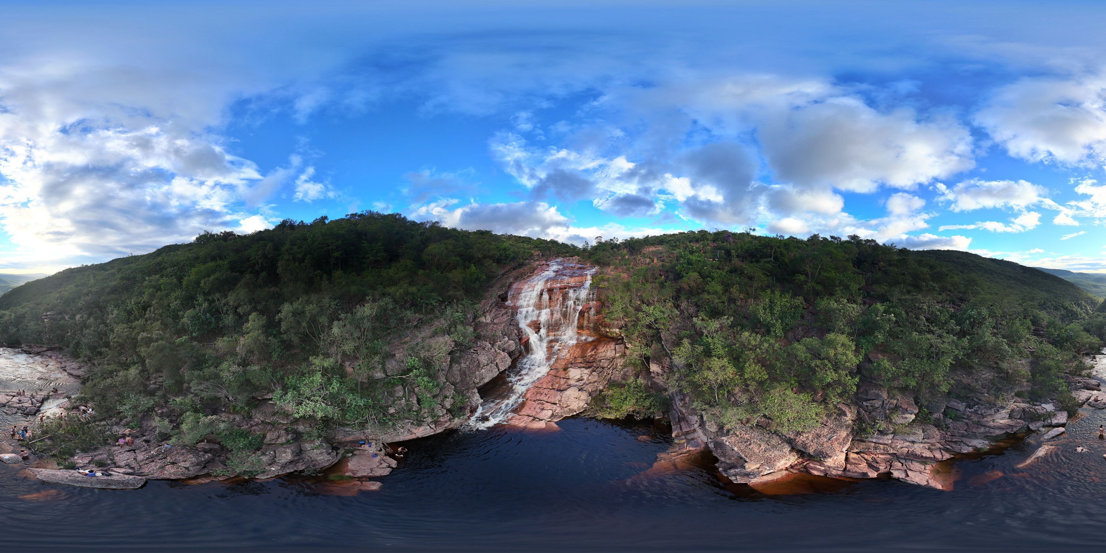 A waterfall cascading down a rocky cliff surrounded by dense forest.