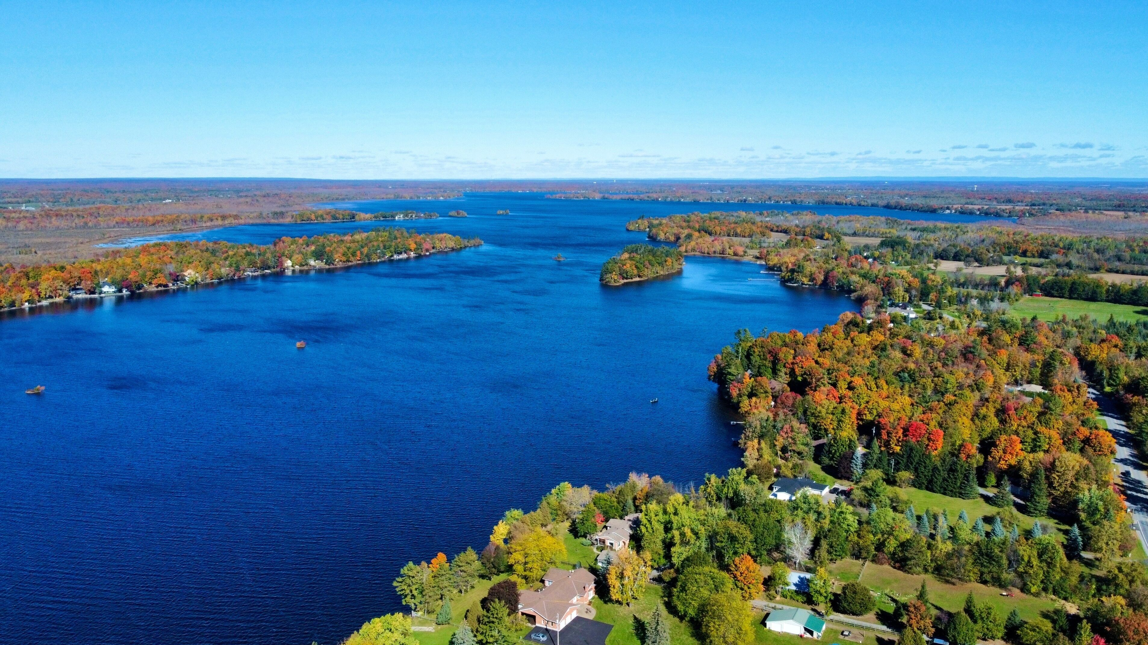 A lake surrounded by autumn-colored trees and houses.