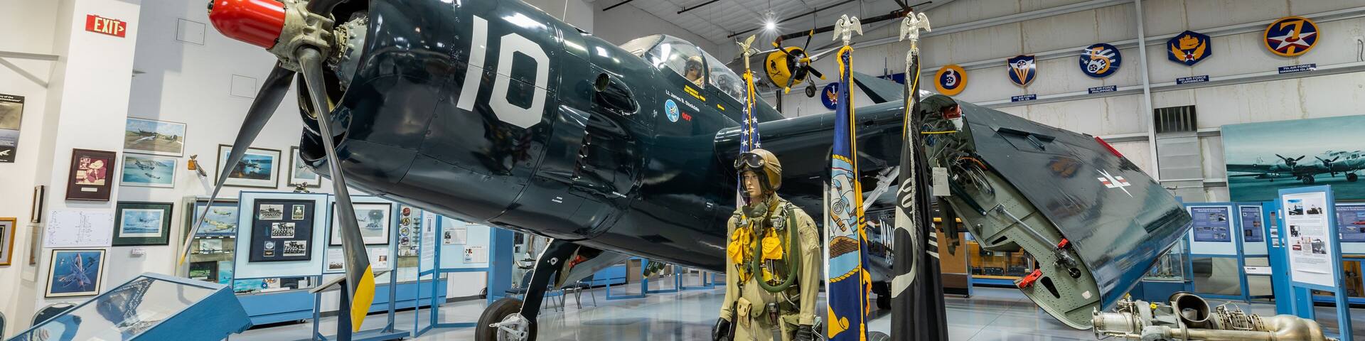 A vintage military aircraft with the number 10 on its side, a pilot mannequin, and various military insignia on the walls.