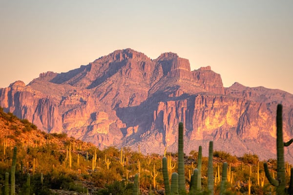 Une chaîne de montagnes, avec des cactus au premier plan et une lune dans le ciel.