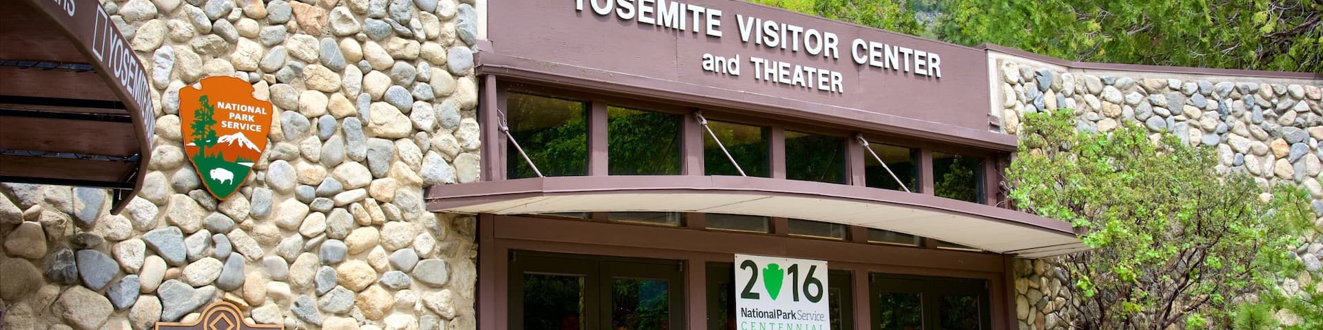The Yosemite Visitor Center and Theater with a stone facade and a sign indicating the year 2016.