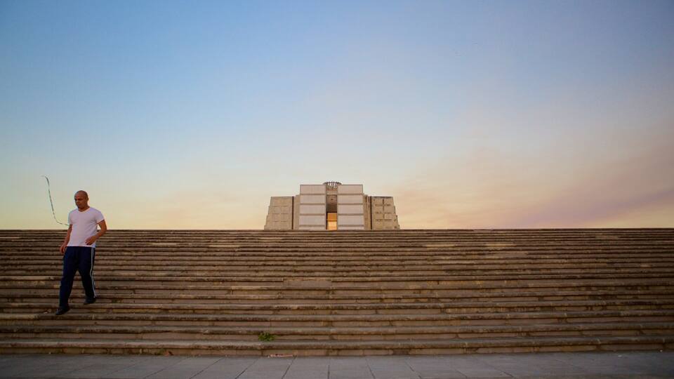 A man standing on stone steps with a building in the background.
