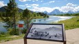 A scenic view of a lake with mountains in the background and a wildlife protection area sign.