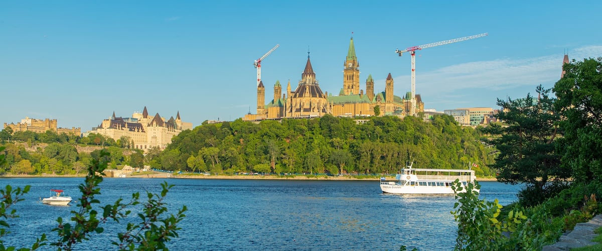 A river with a boat, a castle, and construction cranes.