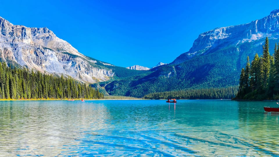 A calm lake surrounded by mountains and dense forests.