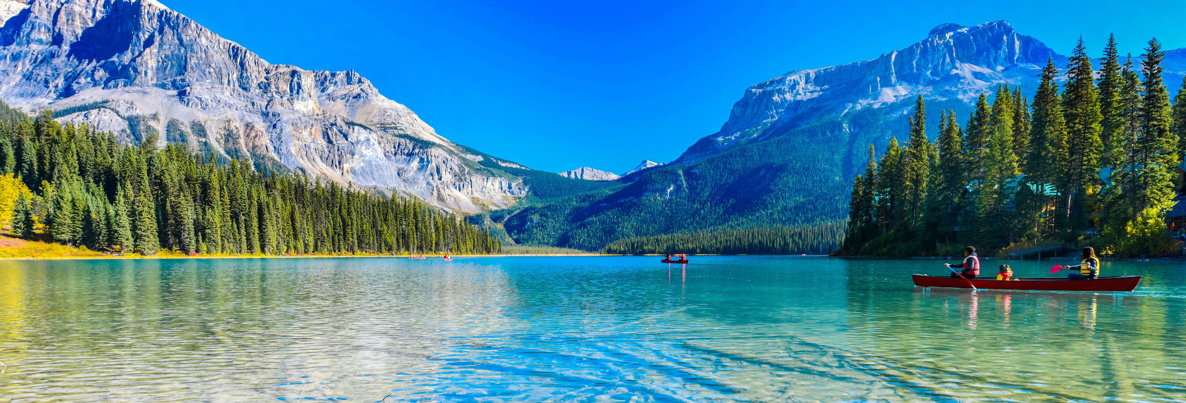 A calm lake surrounded by mountains and dense forests.