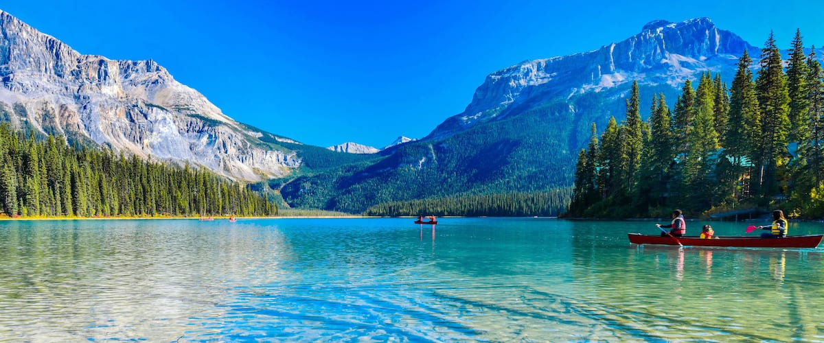 A calm lake surrounded by mountains and dense forests.