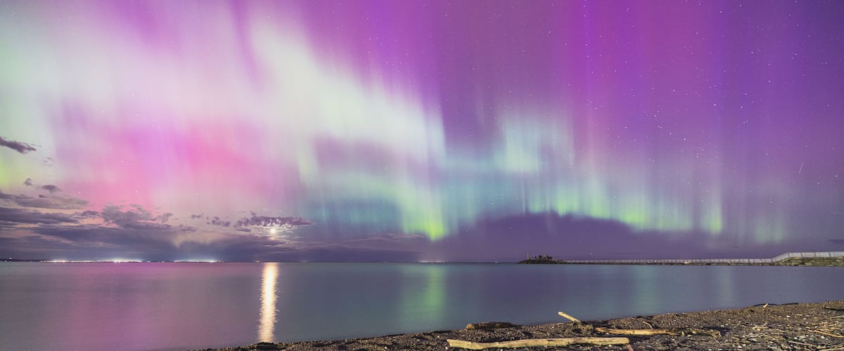 A night sky with the aurora borealis over a calm lake.
