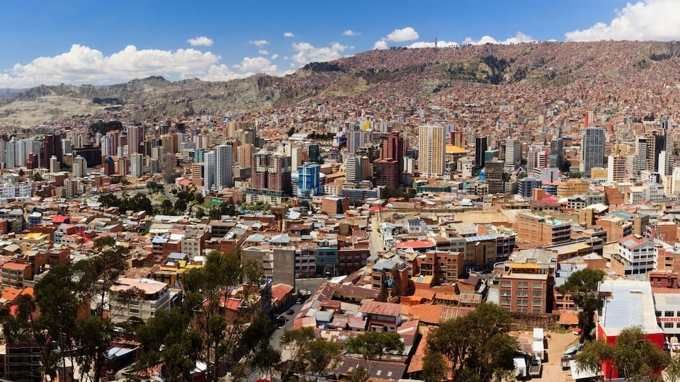 A densely populated city with a mix of high-rise and low-rise buildings, surrounded by hills and mountains.