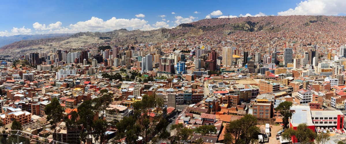 A densely populated city with a mix of high-rise and low-rise buildings, surrounded by hills and mountains.