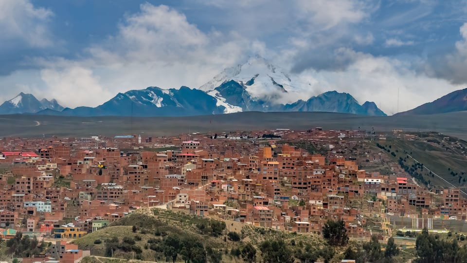 A town nestled in a valley with snow-capped mountains in the background.