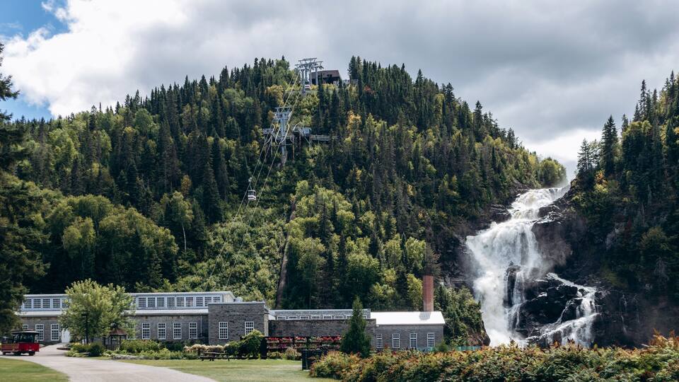 A waterfall, a cable car system, and a building with a red roof.