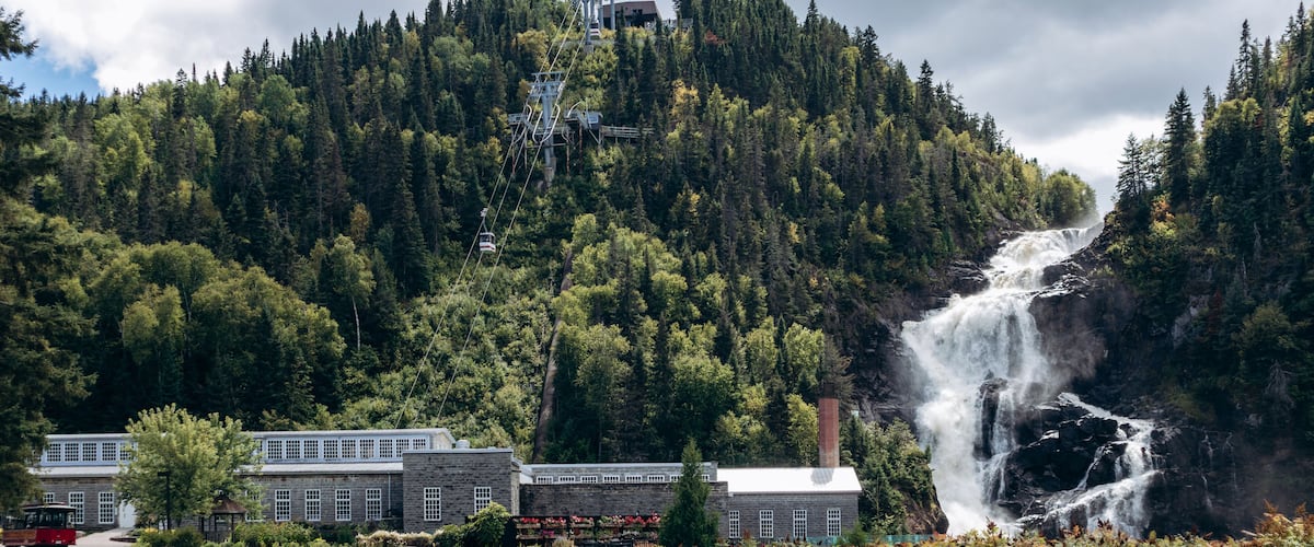 A waterfall, a cable car system, and a building with a red roof.