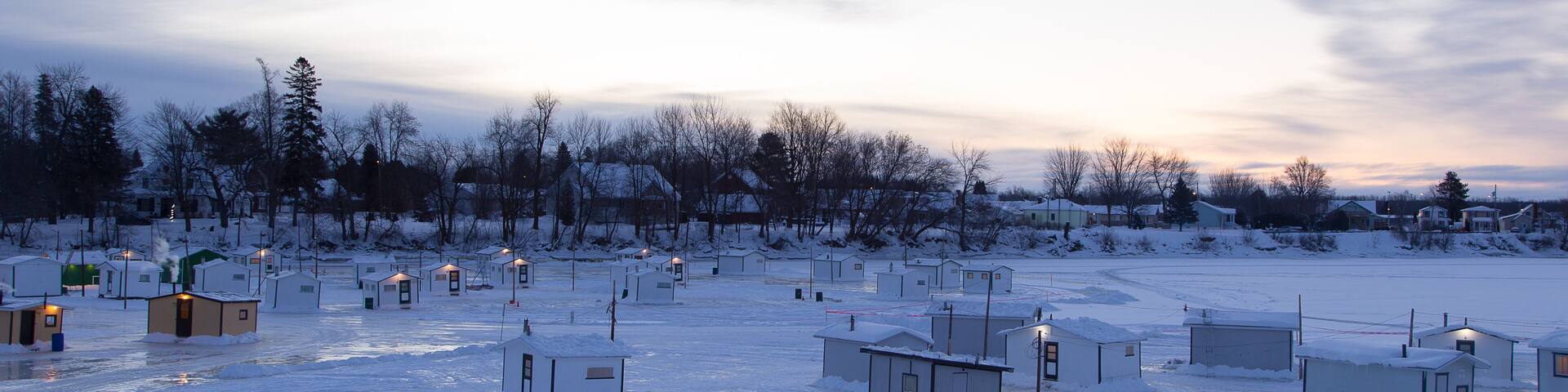 Blue hour view of Atlantic tomcod ice fishing cabins on a frozen river, Sainte-Anne-de-la-Pérade, Quebec, Canada
