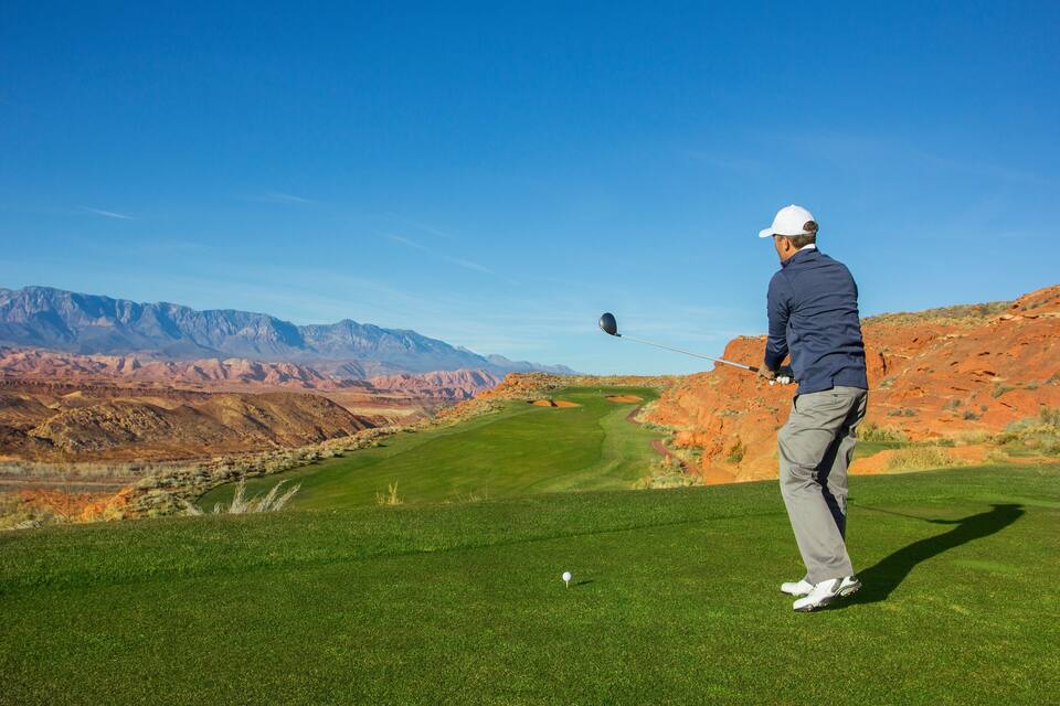 Un golfista en un campo de golf, con montañas al fondo.