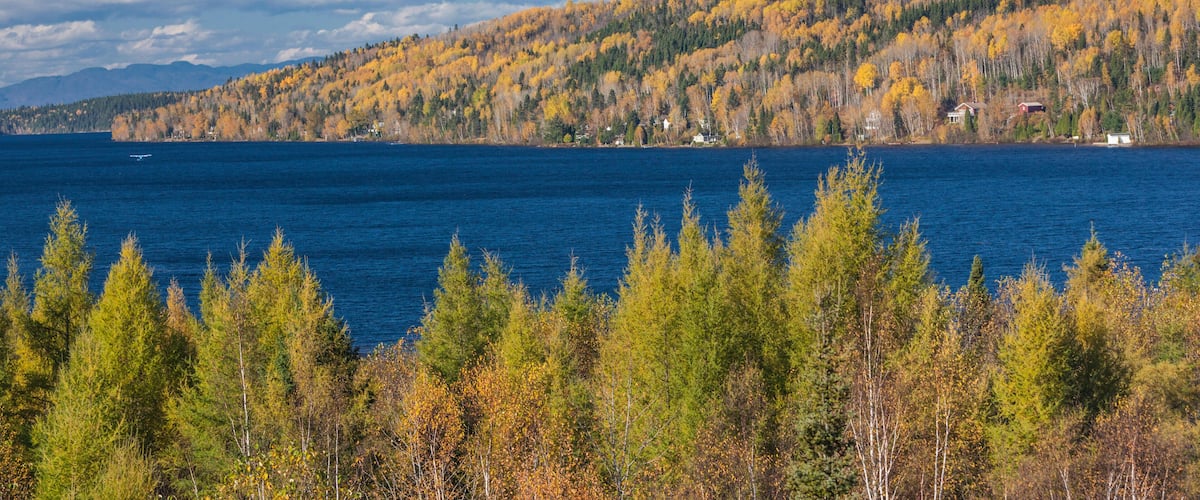 A lake surrounded by autumn-colored trees and a distant mountain range.