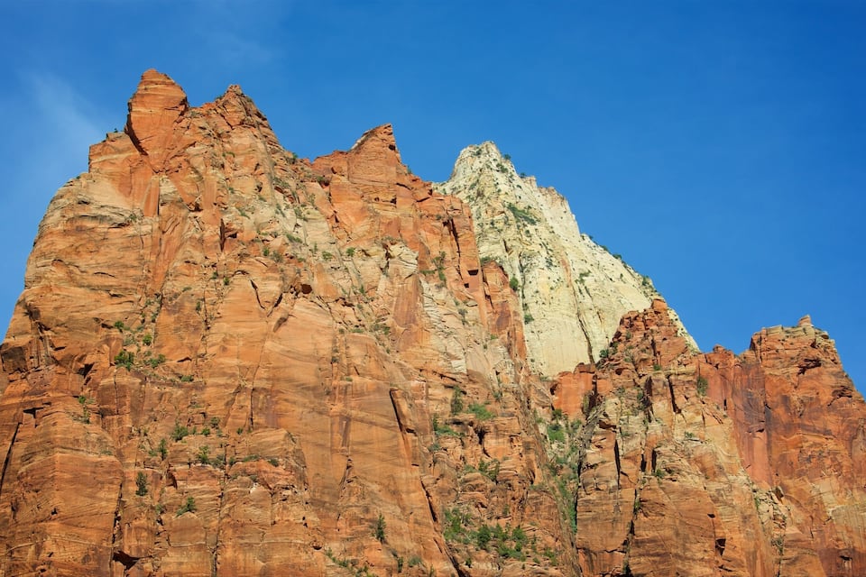 A rugged mountain with red and white rock formations under a clear blue sky.