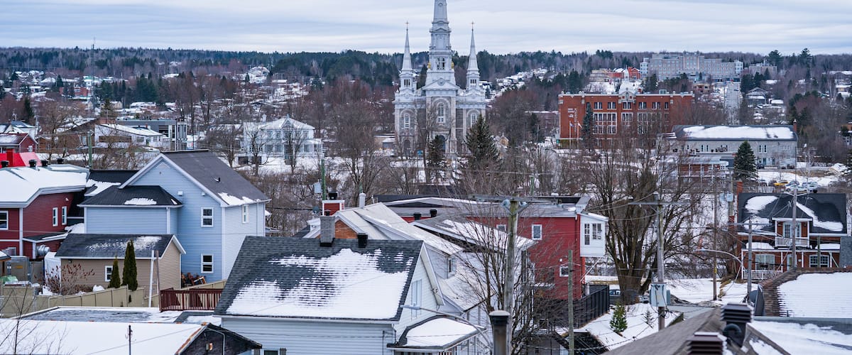 A snowy town with a prominent church steeple and residential buildings.