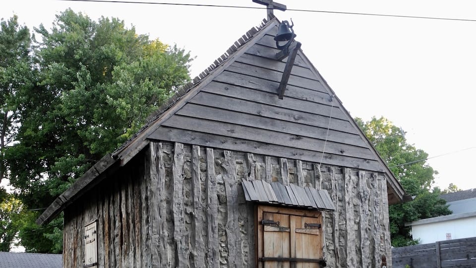 "The first St. Charles Borromeo Church, like this one, was constructed of vertical, hewn logs placed directly in the ground: an architectural style unique to the French in the New World during the 17th and 18th centuries. The church has been rebuilt on its original location. Jesse Francis, a local preservationist with 20 years experience restoring 18th French log buildings, directed the reconstruction. The work was done completely by with period tools in the manner of the 18th century. The church is part of an on-going historical interpretive program based on a re-creation of daily activities in this old French village."