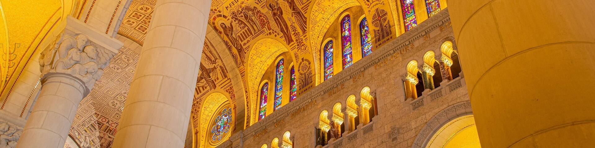 A grand interior with ornate golden ceiling, large columns, and stained glass windows.