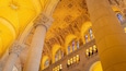 A grand interior with ornate golden ceiling, large columns, and stained glass windows.