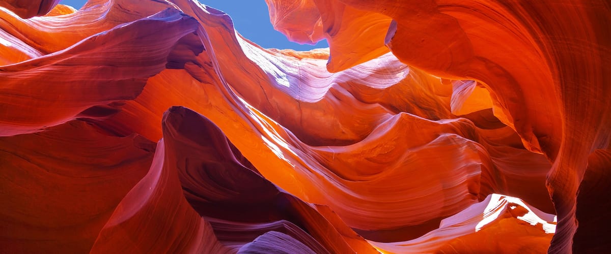 A canyon with smooth, flowing rock formations and a clear blue sky.