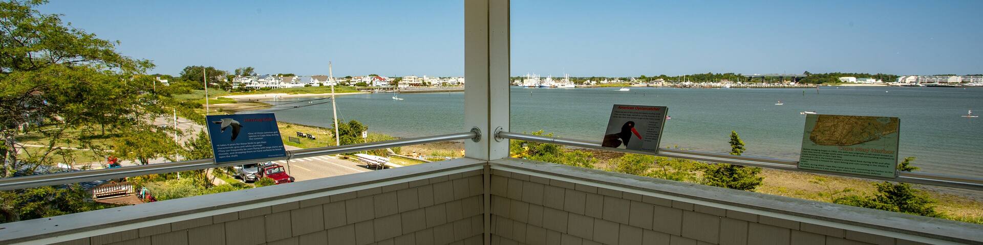 A view from a covered balcony overlooking a waterfront with a sign reading "O'Neill Tower."