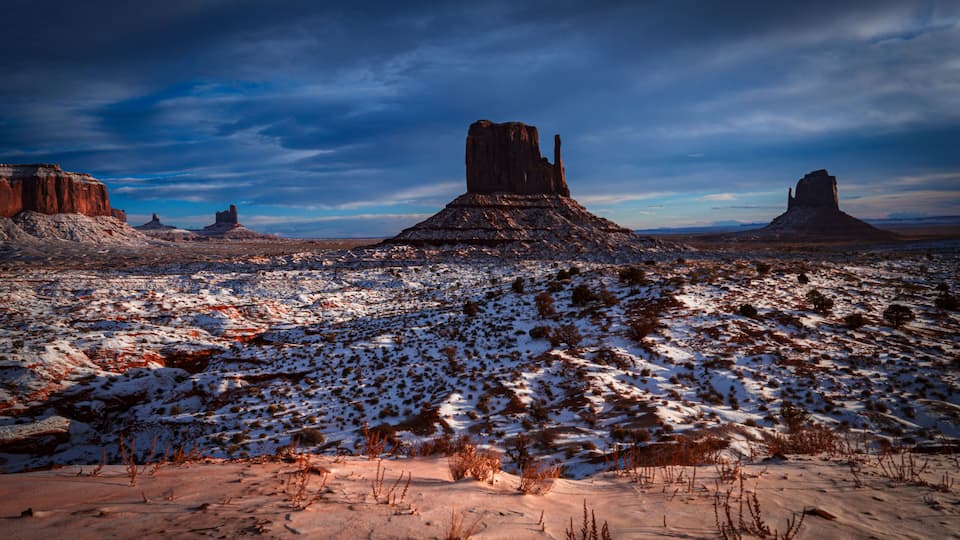A snow-covered desert landscape with prominent rock formations.