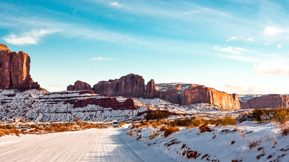 A snow-covered landscape with prominent rock formations and a clear sky.