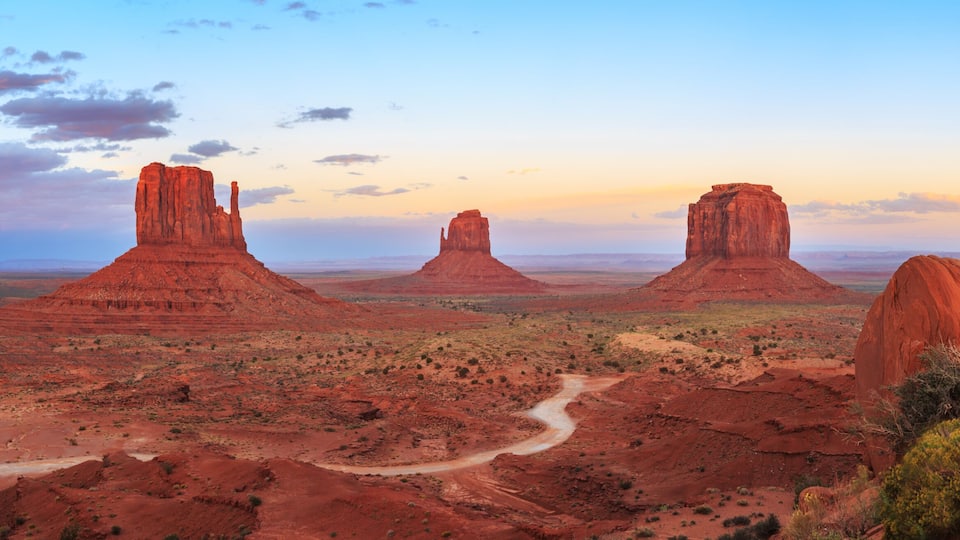 A desert landscape with prominent red rock formations and a winding road.