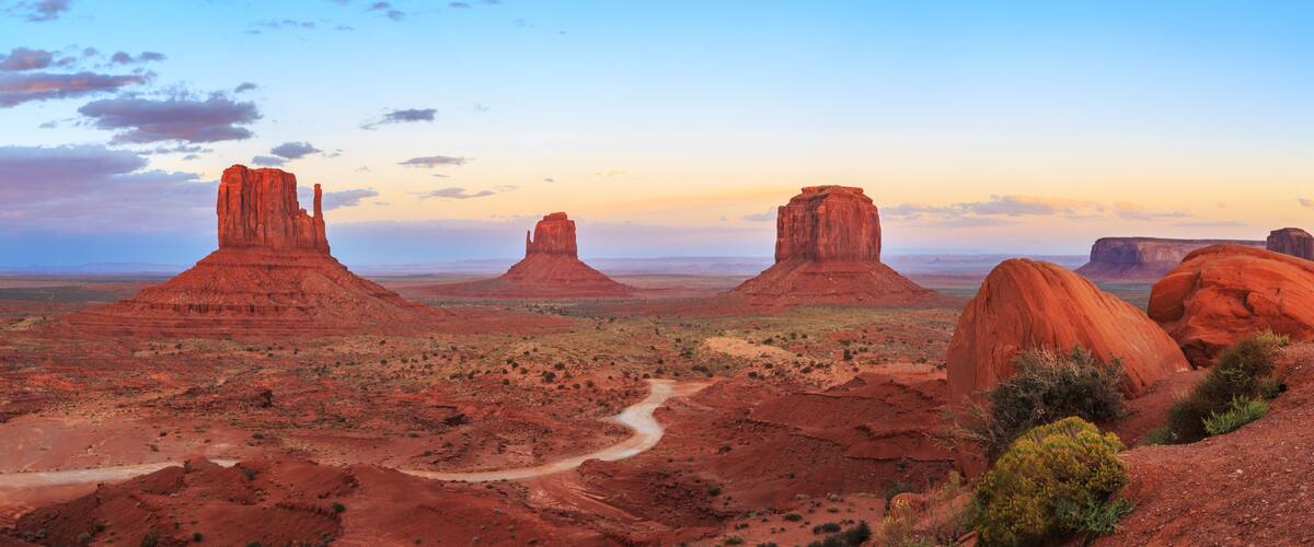 A desert landscape with prominent red rock formations and a winding road.