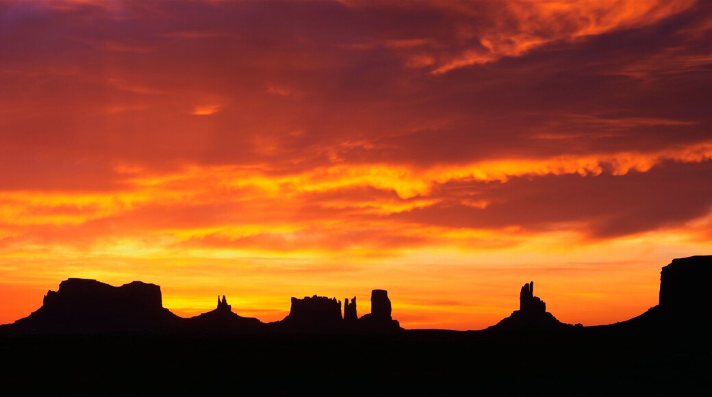 This is sunrise on Monument Valley. The rocks are in silhouette against an orange sky.