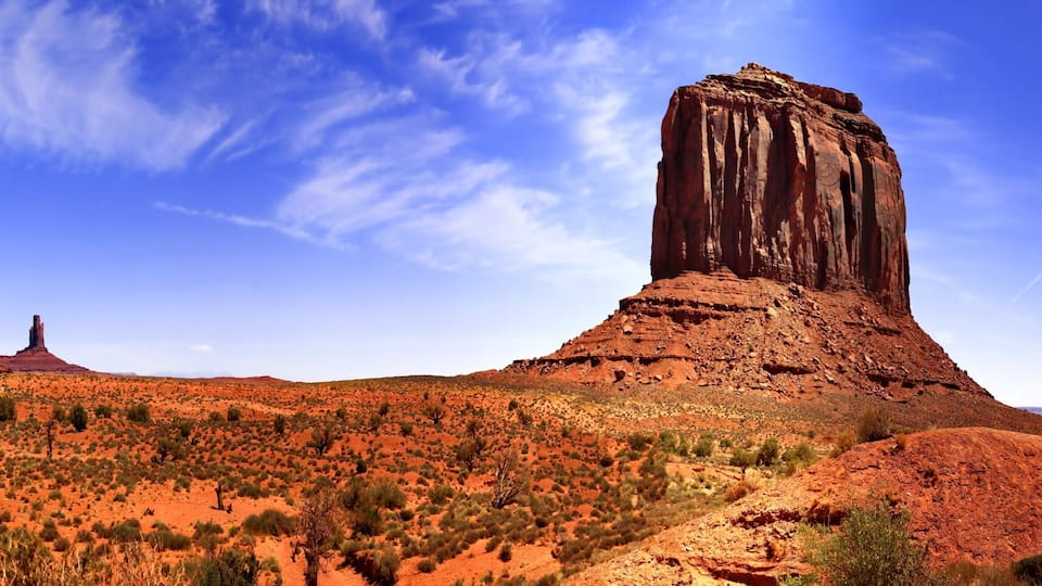 A desert landscape with prominent red rock formations and sparse vegetation.