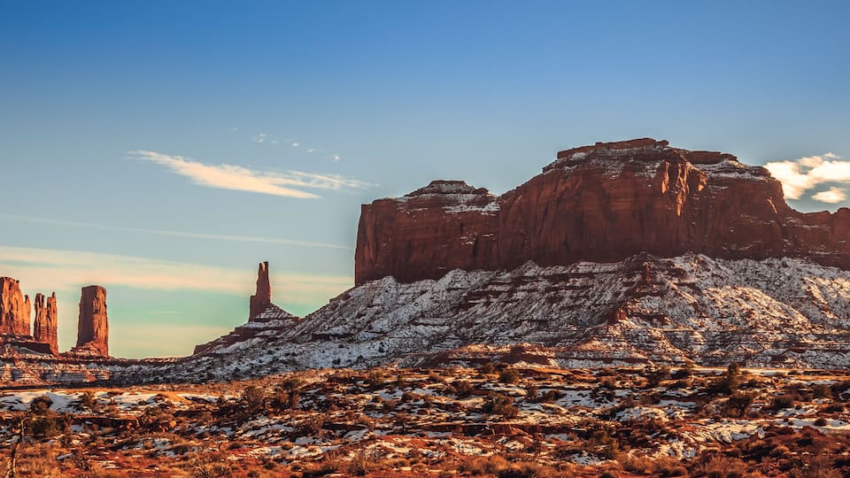 A snow-covered mountain with distinct rock formations and a clear sky.
