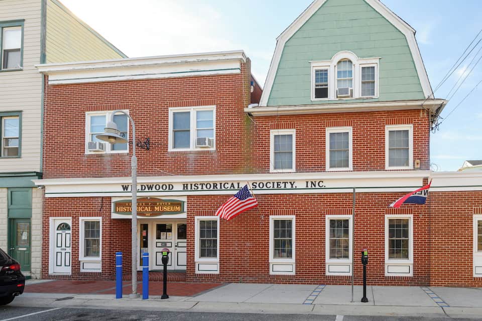 Un edificio de ladrillo con techo verde y un cartel que dice "Wildwood Historical Society, Inc.".