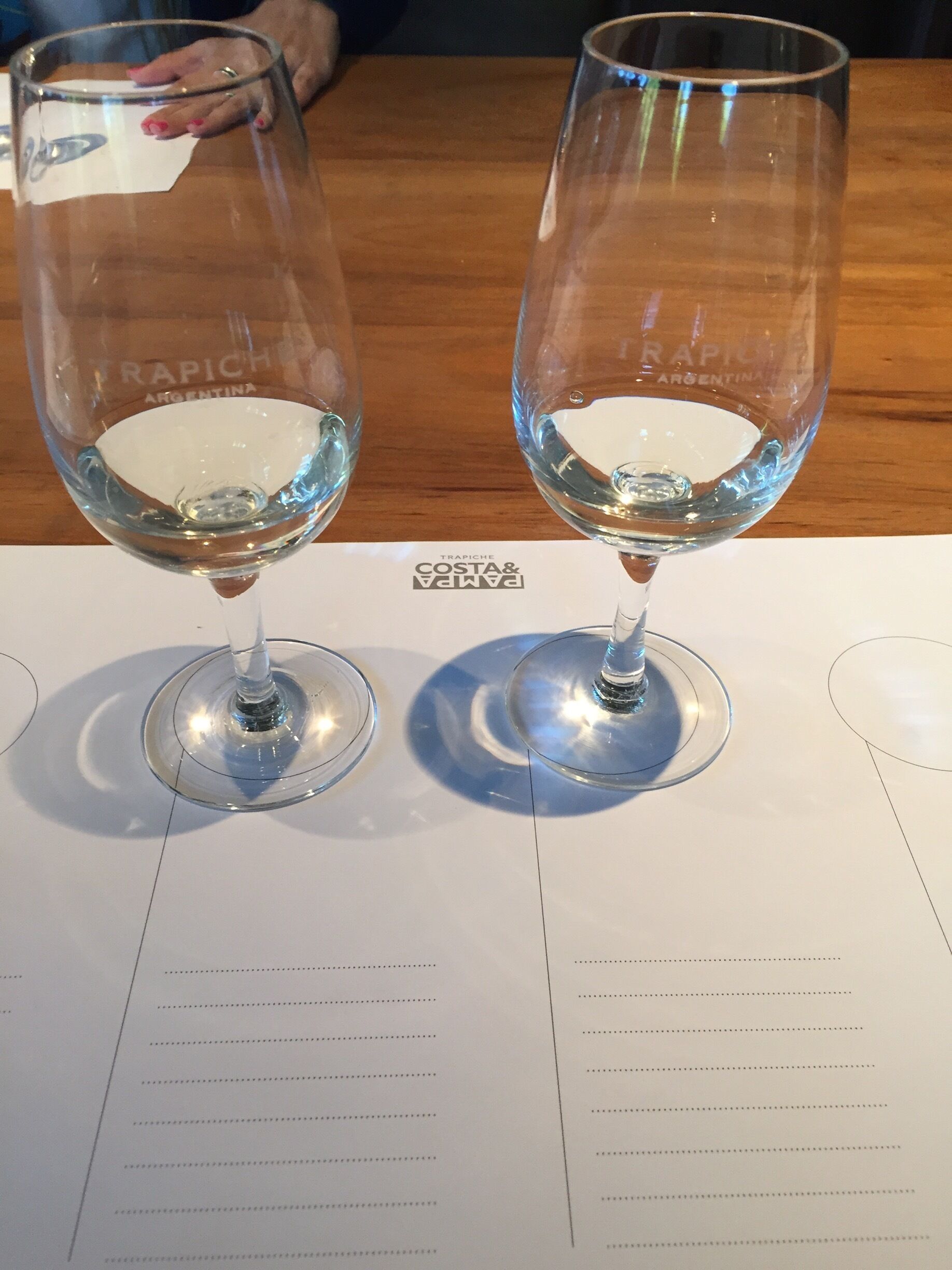 Two empty wine glasses on a table with a menu.