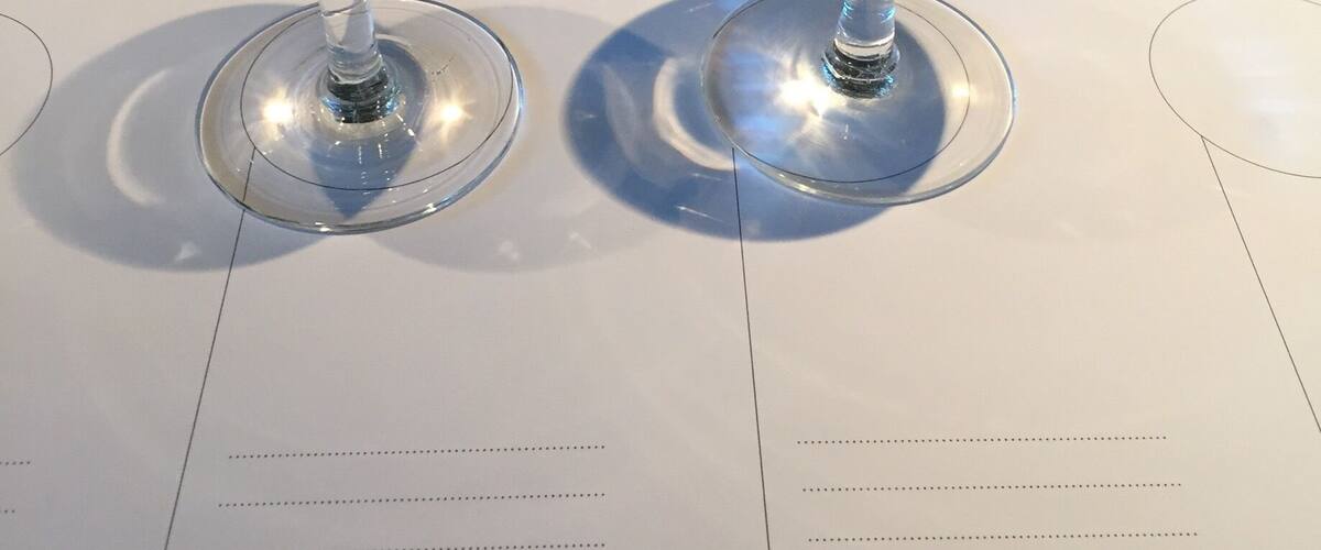 Two empty wine glasses on a table with a menu.