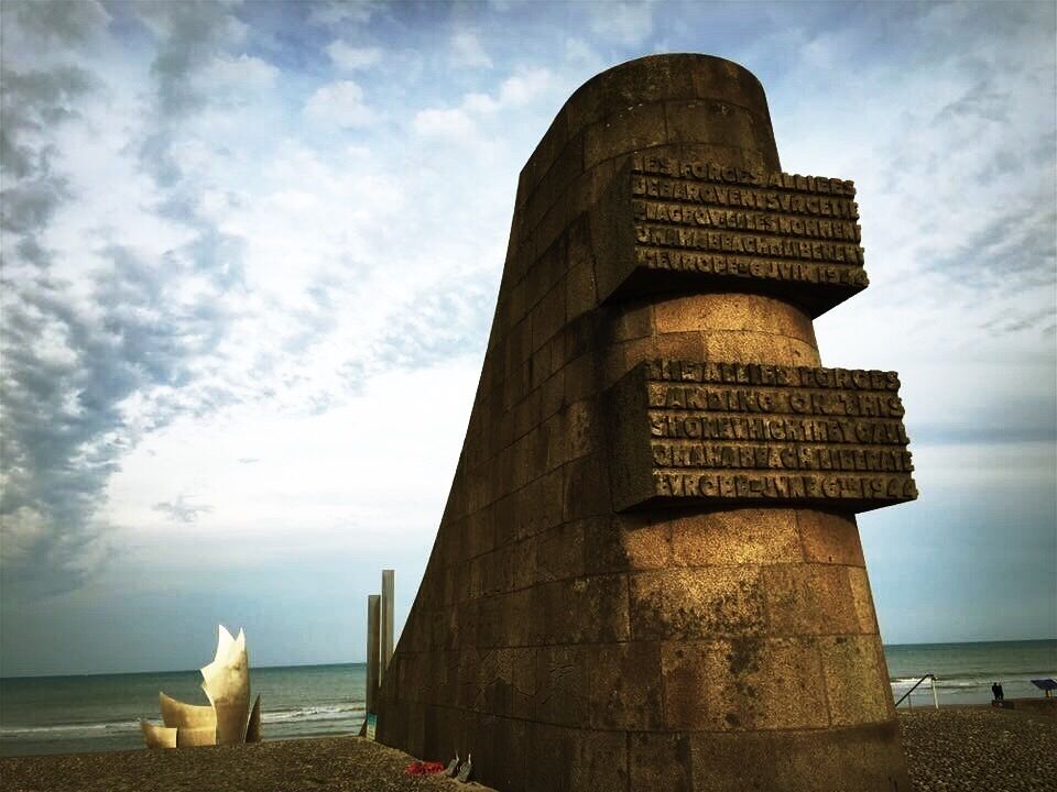 A stone monument with inscriptions by the sea.