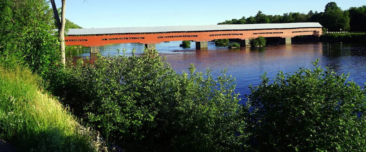 A bridge over a river with lush greenery and trees around.