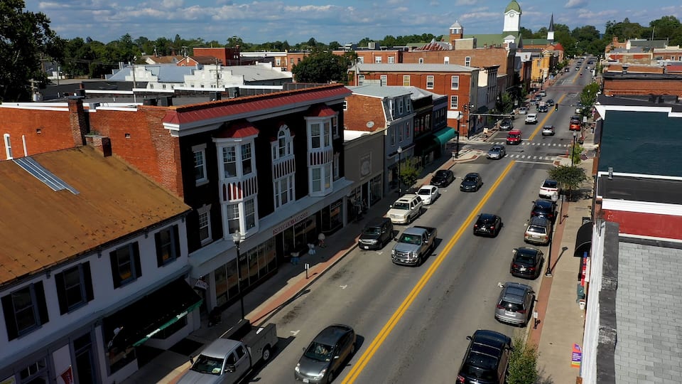 A street lined with historic buildings, a church steeple, and a clear blue sky.