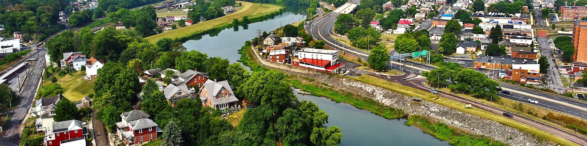 A river winding through a town with houses and a highway.